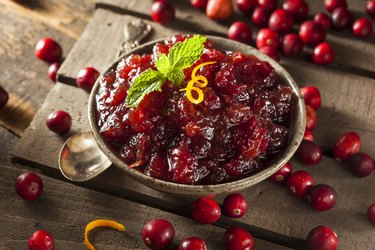 Homemade Red Cranberry Sauce on a table garnished with orange zest.