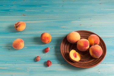 A few ripe, velvety peaches on blue wooden table. Sunny