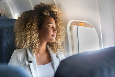 a woman sleeping on an airplane, as a way to prevent jet lag