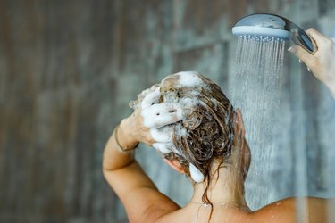 back view of a person washing their hair with anti-dandruff shampoo, as a natural remedy for dandruff