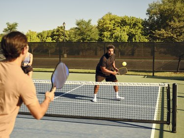 两个人玩pickleball法院在夏天。