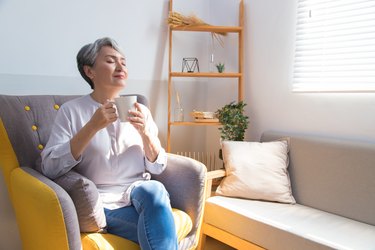 woman at home smiling and drinking a cup of tea, as a natural remedy for upset stomach