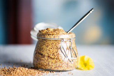 Whole-grain mustard in a jar on a table with visible seeds for weight loss