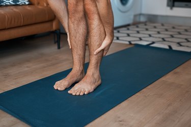 close up of person stretching holding calves