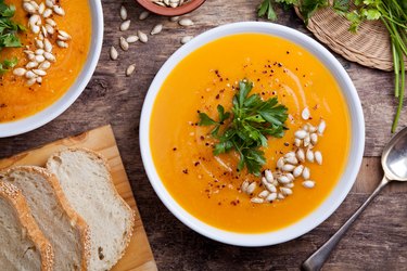 an overhead photo of a bowl of homemade pumpkin soup topped with pumpkin seeds