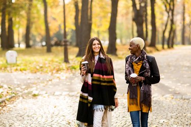 Two young multiethnic female friends walking in park to improve their heart health