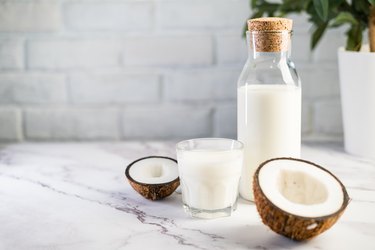 Fresh coconut milk in glass bottle, vegan non dairy healthy drink.