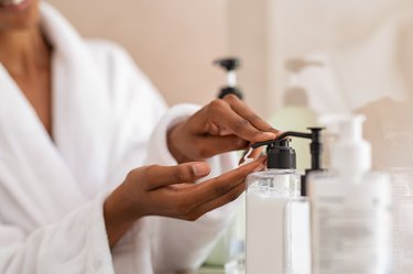 Woman taking body moisturizer from dispenser