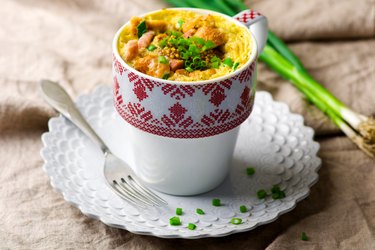 Mug omelet prepared in microwave on a plate next to fork on tabletop