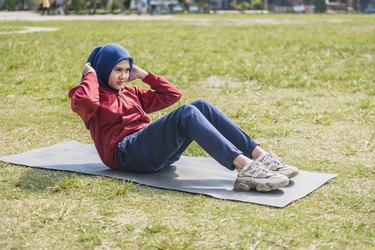 woman in hijab doing crunches on grass