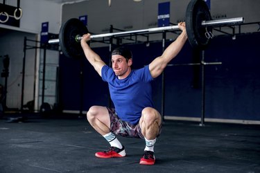 male athlete doing an overhead barbell press