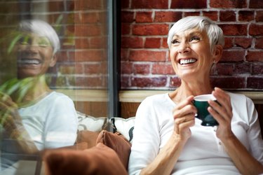 an older adult drinking green tea to reduce inflammation in front of a brick wall in a cafe