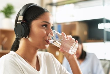 La giovane persona ispanica ha assegnato la femmina alla nascita acqua potabile da un bicchiere chiedendosi perché l'acqua purificata è cattiva per te dal microrganismo svantaggi