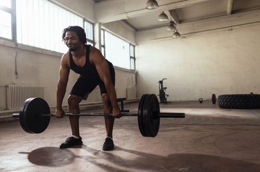 Man doing a deadlift with loaded barbell in a garage