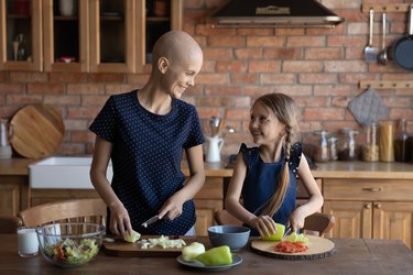 Happy sick mother cancer patient and little daughter cooking together