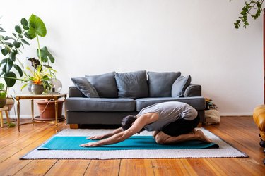 Person in child's pose (Balasana) at home to demonstrate how long you should hold a yoga pose.