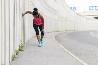 Runner wearing pink tank top and black leggings with knee injury