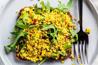 Tofu scramble toast with greens on rye bread, top view. Healthy vegan food concept.