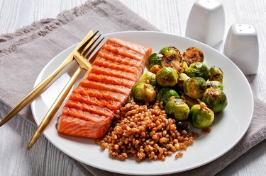 grilled salmon, brussel sprouts, spelt on a plate