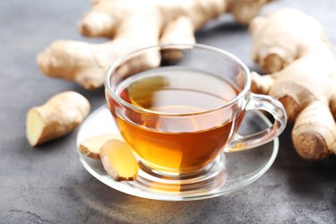 Cup of tea with ginger root on grey wooden table, as a natural remedy for cough