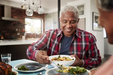 Older Couple Enjoying Meal Around Table At Home