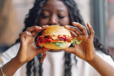 Woman eating a high-sodium burger with foods that make you retain water