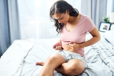 Person wearing a pink shirt and grey shorts injects themselves with insulin in the morning, to reduce dawn effect