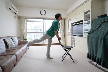 Asian senior woman exercising at home with chair, as a way to promote healthy aging