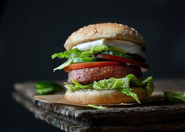 faux meat burger with lettuce and tomato on a bun, as an example of foods bad for brain health