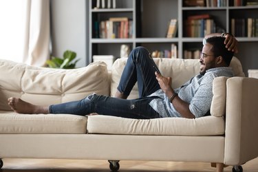 Relaxed young african ethnicity man using mobile phone.