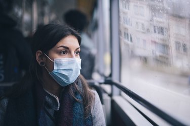 woman riding a bus and wearing a surgical face mask, as a herpes remedy