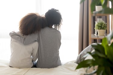 back view of friends sitting together and comforting one another, as an example of how to stay healthy