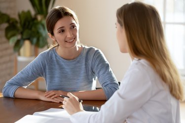 Smiling young woman patient listening to doctor at meeting