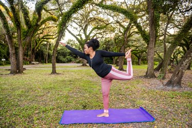 Yogi Balances in Dancer Pose While Doing Yoga at the Park