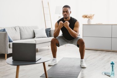 Person performing a squat in their living room to demonstrate how many days a week you should train your legs.