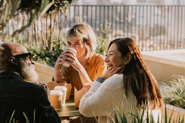 Person with long brown hair in a white sweater spending time at a coffee shop with friends, to help them deal with the symptoms of antidepressant withdrawal.