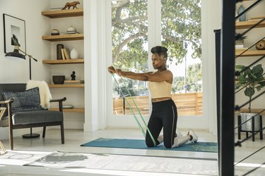 woman over 50 doing a resistance band workout in her living room
