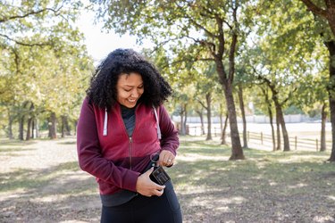 Young person with type 2 diabetes checks insulin pump and blood sugar monitor while hiking outdoors