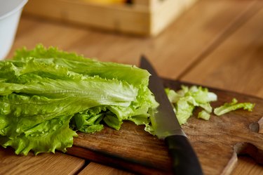 Wooden cutting board and knife with cut leaf of lettuce