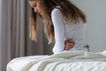 Close up person holding their stomach in pain