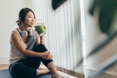 年轻女子在运动后喝一杯冰沙，作为治疗胃灼热的自然疗法