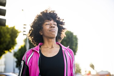 Person in workout clothes outside practicing breathing after exercising to promote better recovery.