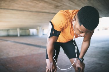 exhausted man taking a break to stop and breathe while running