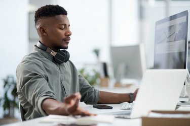 Young Black man meditating in at his desk at work at the best time of day to meditate