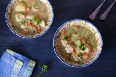 Bowl of chicken cooked in the slow cooker as stew with vegetables on dark gray background