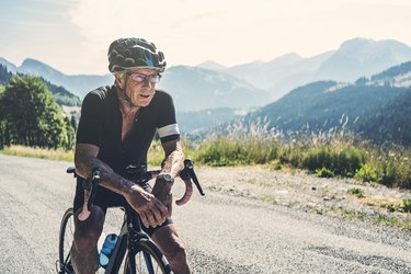 older adult rides their bike, one of the best sports for seniors, in a beautiful scenic mountainous area