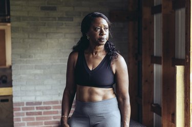 Portrait of person wearing a sports bra and leggings standing in cross training gym