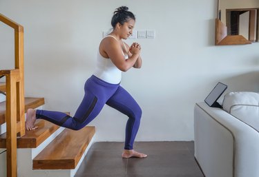 Woman doing Bulgarian split squats during at-home workout on her stairs