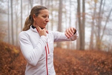 upper body woman taking her pulse after running in fog on cold autumn morning