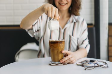 woman Pouring cream in cold brew coffee